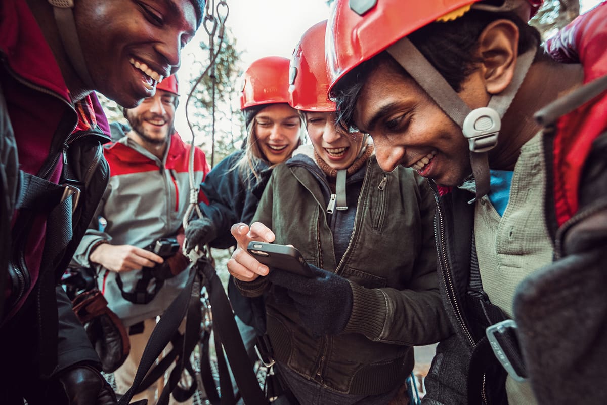 Group of people wearing helmets preparing to rock climb. Smiling faces.