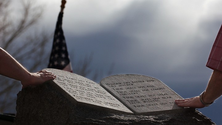 Two people touch the Ten Commandments Monument