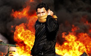 A protestor against the backdrop of a burning flame. 