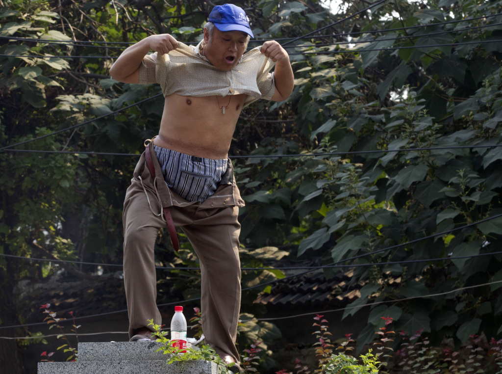One of the Jinan sideshows. A petitioner lifts his shirt to show his injuries as he climbs a pillar to protests his own grievances near the Jinan Intermediate People's Court in Jinan in eastern China's Shandong province on Thursday Aug. 22, 2013. Ousted populist Chinese politician Bo Xilai went on trial Thursday on charges of bribery, embezzlement and abuse of power, marking the ruling Communist Party's attempts to draw a line under one of its most lurid political scandals in decades. Individual protestors have turned up at the court hoping to take advantage of media attention around Bo's trial to air their own grievances about China's legal system. (AP Photo/Ng Han Guan