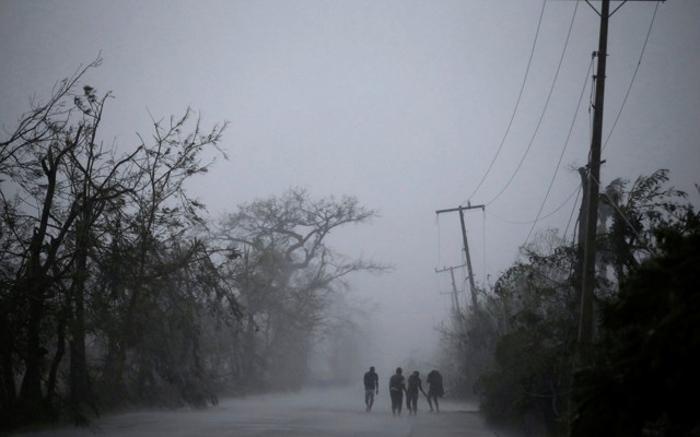 People walk on the road as rain falls during Hurricane Matthew in Les Cayes, Haiti, on October 4.