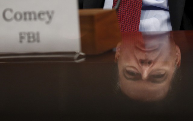 Comey's reflection seen in a polished desk as he testifies at a world wide threat hearing on Capitol Hill in Washington.