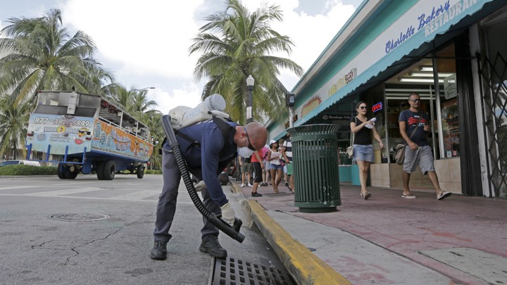 A mosquito control inspector sprays a chemical mist into a storm drain in Miami Beach, Florida, on August 23, 2016.