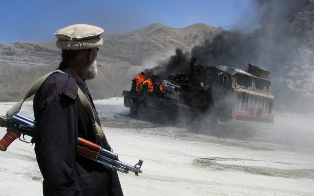 A Pakistani security official stands near a burning vehicle after it was attacked in the Balochistan region. 