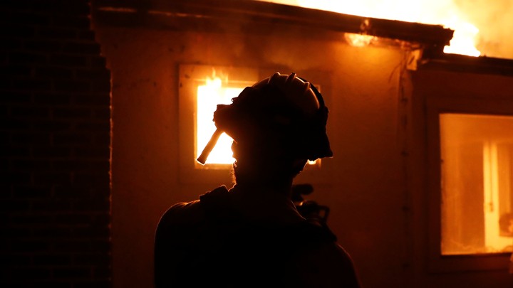 A firefighter monitors a burning structure while battling the Clayton Fire at Lower Lake in California.