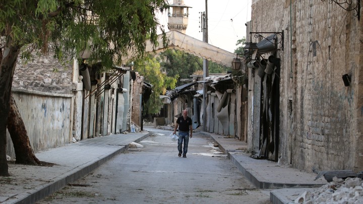 A man walks near damaged shops in the Syrian city of Aleppo