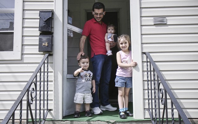 Mohammad Zkrit and three of his four children stand on the porch of their newly-rented home in Erie, Pennsylvania. The family fled the ongoing civil war in Syria and have been resettled in the United States.