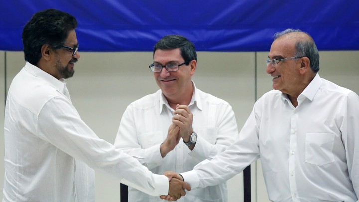 FARC lead negotiator Ivan Marquez, left, and Colombia's lead government negotiator Humberto de la Calle, right, shake hands while Cuba's Foreign Minister Bruno Rodriguez looks on, after signing a final peace deal in Havana, Cuba.