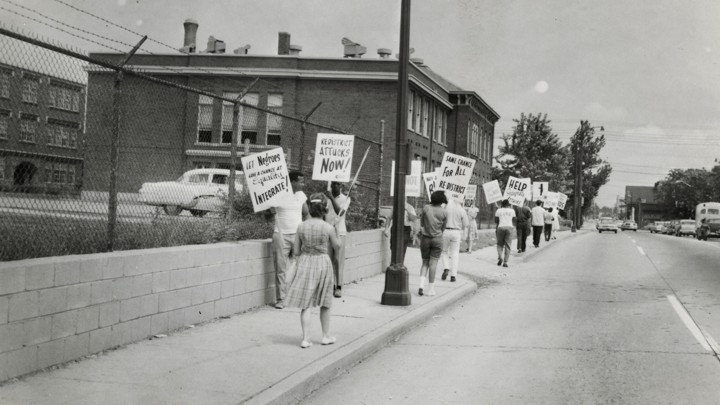 Protestors carried signs asking for school redistricting and integration. They were on the sidewalk in front of IPS School 17 in the 1960s.