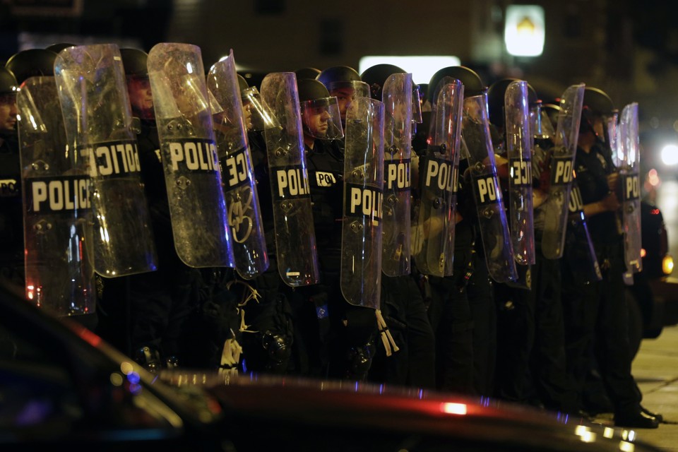 Police officers protected by clear shields move in single formation on a crowd during a protest Milwaukee on Sunday, August 14, 2016. 