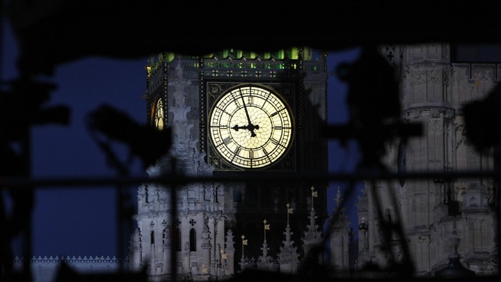 An illuminated clock on the face of Big Ben shines brightly against a dark sky.