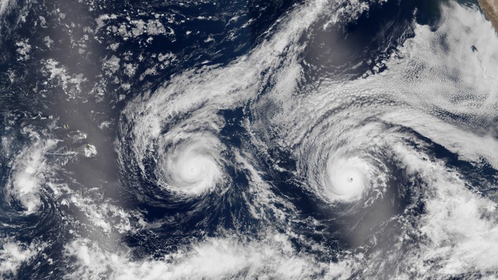 A tropical storm and a hurricane approach Hawaii as seen from satellite images.