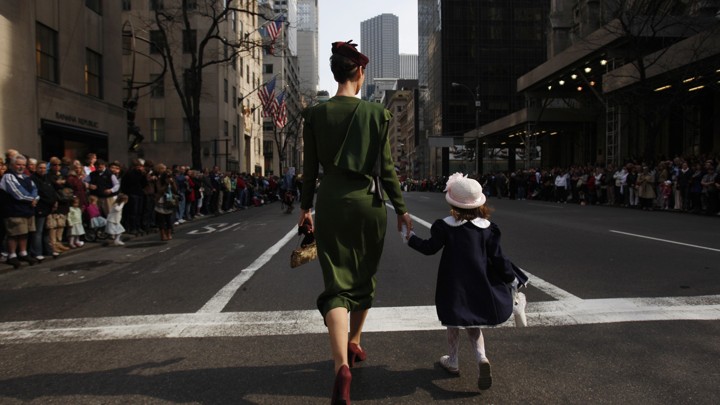 The backs of a mother and daughter, walking hand-in-hand down a street in New York City