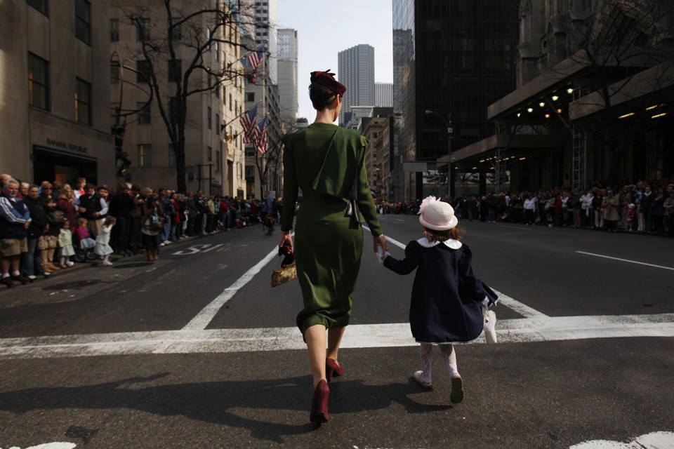 The backs of a mother and daughter, walking hand-in-hand down a street in New York City