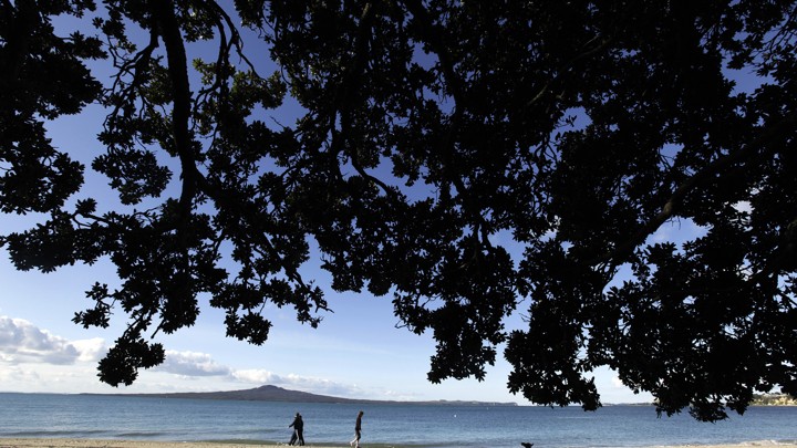 People walk along Kohimarama Beach in Auckland in 2011.