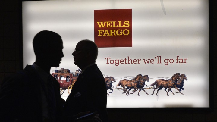 Patrons stand outside a Wells Fargo bank