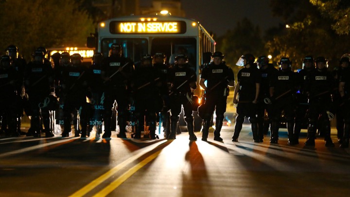 Riot police gather near protesters after a midnight curfew, as demonstrators gather by the police station to protest the police shooting of Keith Scott in Charlotte, North Carolina, U.S., September 24, 2016.
