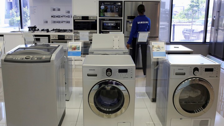 Samsung washing machines are seen as an employee inspects refrigerators at a Samsung display store in Johannesburg, October 3, 2013