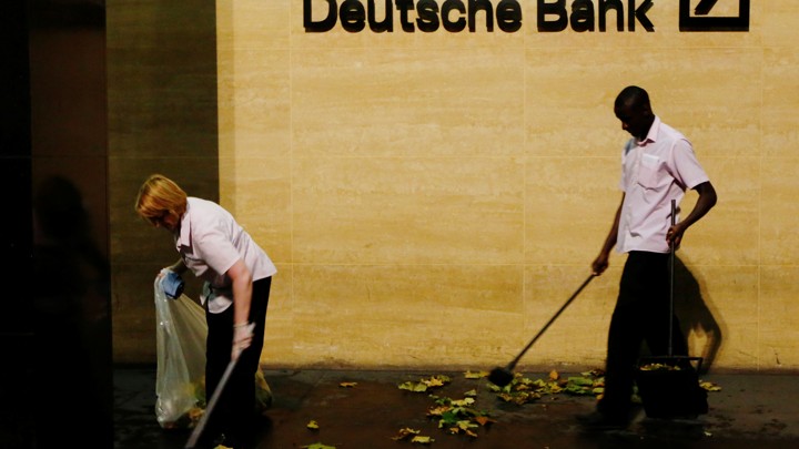 Workers sweep leaves outside Deutsche Bank offices in London, Britain December 5, 2013.
