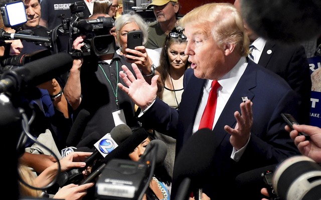 Donald Trump is surrounded by reporters holding cameras and microphones as he addresses the media during the National Federation of Republican Assemblies, in Nashville, in 2015.