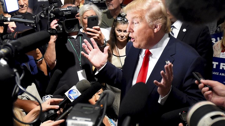 Donald Trump is surrounded by reporters holding cameras and microphones as he addresses the media during the National Federation of Republican Assemblies, in Nashville, in 2015.