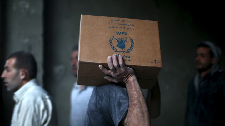 A man unloads boxes from an aid convoy in eastern Damascus, Syria.