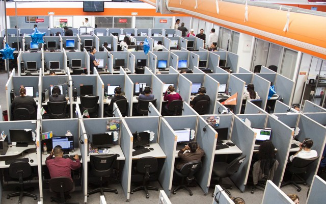 Workers sit at desks in a call center
