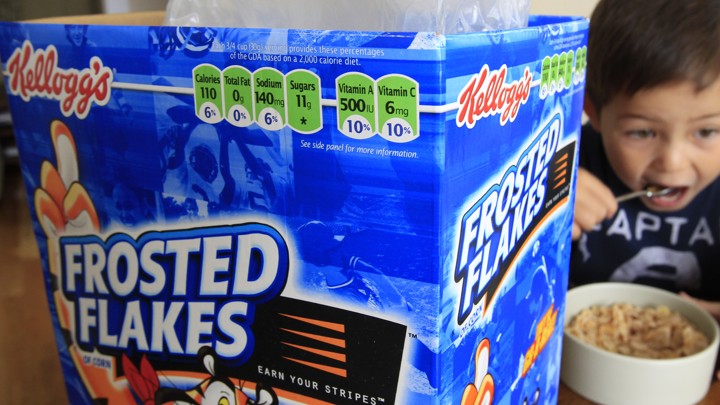 A child eats a bowl of Frosted Flakes.