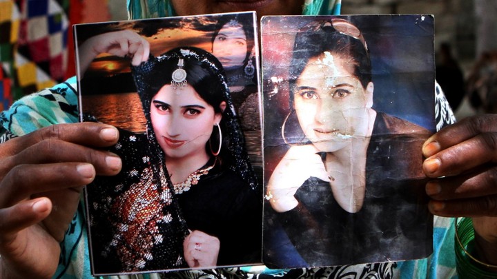 A family member holds pictures of singer and Internet celebrity Qandeel Baloch, who was killed in July in an honor killing allegedly committed by her brother.