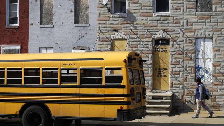 A student walks past vacant row houses to a waiting school bus as school gets out for the day in Baltimore.