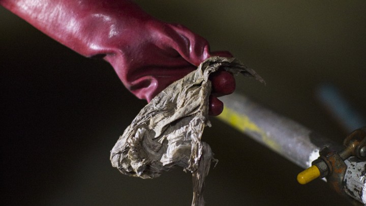 A gloved hand holding a wet wipe found in the Northern Outfall Sewer, London
