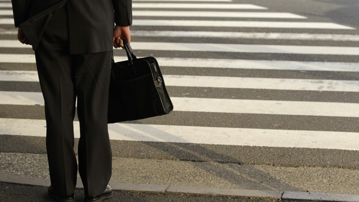 A businessman waits on a street corner.