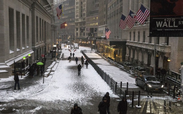 Pedestrians walk down Wall Street in the winter.
