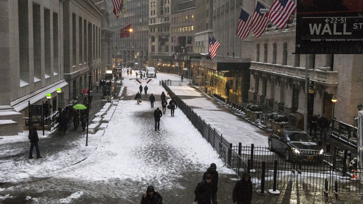 Pedestrians walk down Wall Street in the winter.