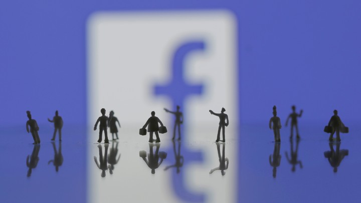 Several human minifigures stand in front of the Facebook logo
