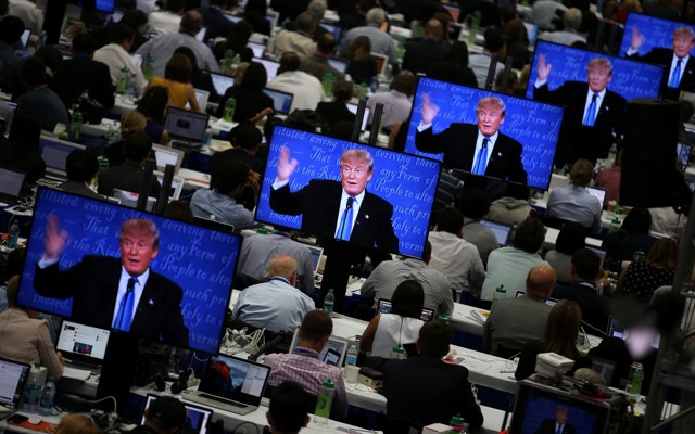 Reporters watch Donald J. Trump on television screens during the first presidential debate.