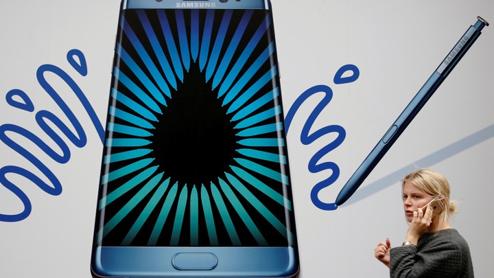 A woman speaks on an Apple phone as she passes an advertisement for the Samsung Galaxy Note 7 in London, Britain, September 2, 2016.