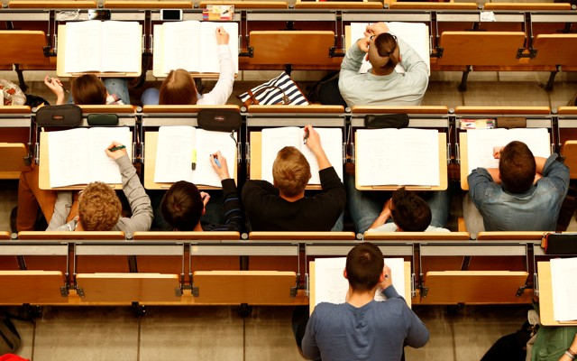An overhead shot of students with open notebooks on desks in a lecture hall