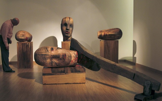 A large wooden sculpture by Mustafa Al depicts heads severed by an axe.