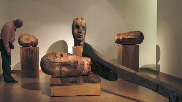 A large wooden sculpture by Mustafa Al depicts heads severed by an axe.