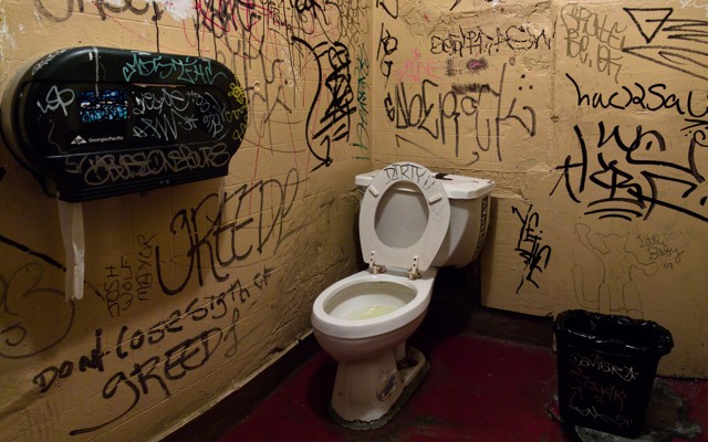 A dirty bathroom with graffiti on the walls