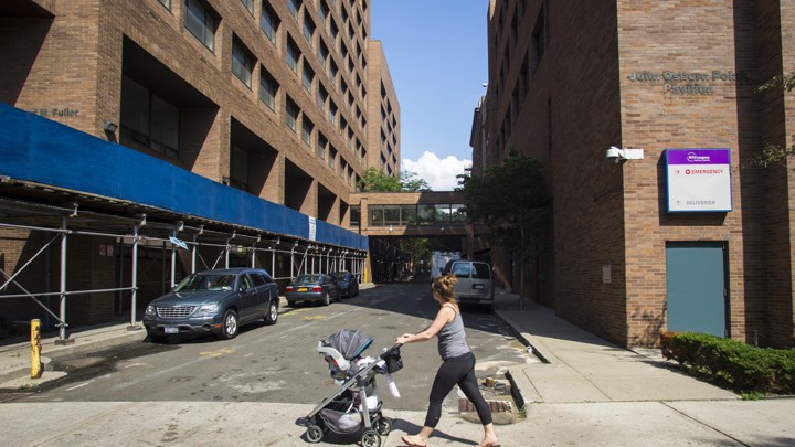 A young woman pushes a stroller past Long Island College Hospital in Brooklyn, New York.