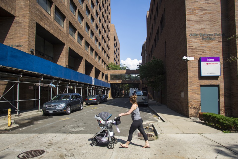 A young woman pushes a stroller past Long Island College Hospital in Brooklyn, New York.