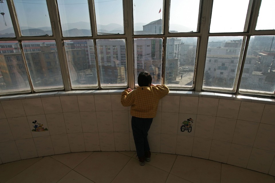 A child with autism looks out a window at the Xining Orphan and Disabled Children Welfare Center, in China.