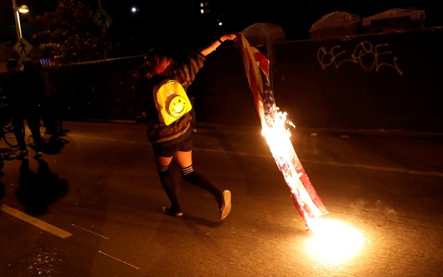 A demonstrator burns an American flag to protest the election of Donald Trump on November 10 in Oakland, Calif.