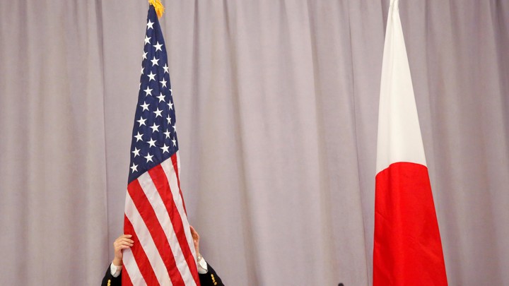 A worker adjusts the U.S. flag before Japanese Prime Minister Shinzo Abe addresses media following a meeting with President-elect Donald Trump in New York City on November 17, 2016.