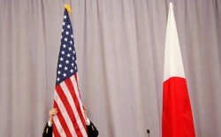 A worker adjusts the U.S. flag before Japanese Prime Minister Shinzo Abe addresses media following a meeting with President-elect Donald Trump in New York City on November 17, 2016. 