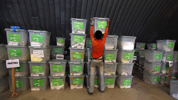 An election worker reaches for a ballot box during the audit and recount process, at a warehouse in Kabul, October 5, 2009.