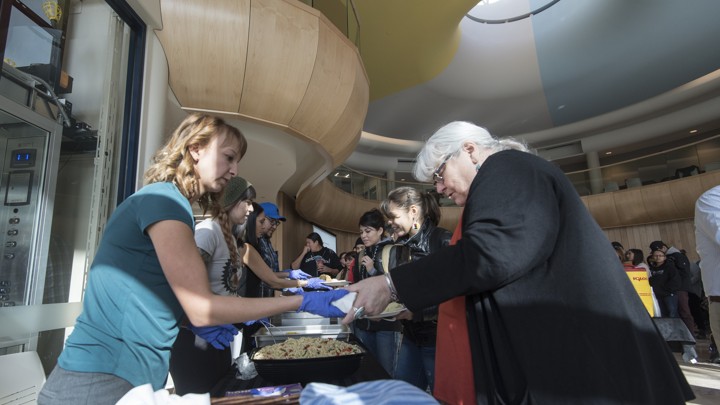 A woman is handed a plate of food. A line of other people is behind her.