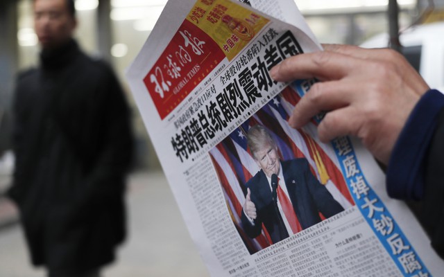 A man reads a newspaper with the headline of "U.S. President-elect Donald Trump delivers a mighty shock to America" at a news stand in Beijing.